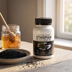 The bottle on a kitchen table beside honey and a dish of black seeds